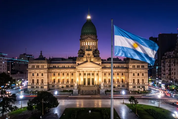 Argentine National Congress building at night, with the Argentine flag