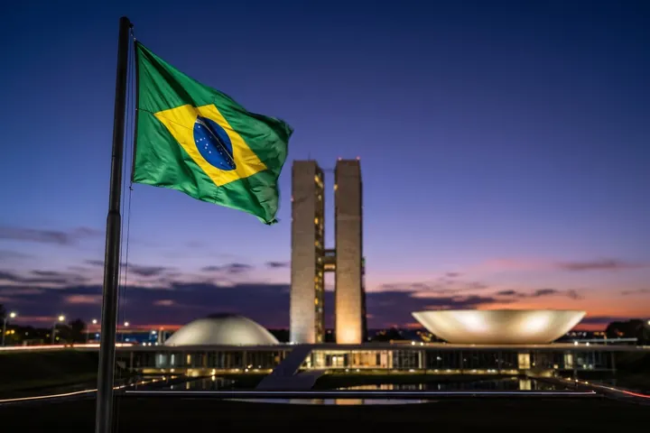 National Congress of Brazil in Brasília at dusk, with the Brazilian flag in the foreground