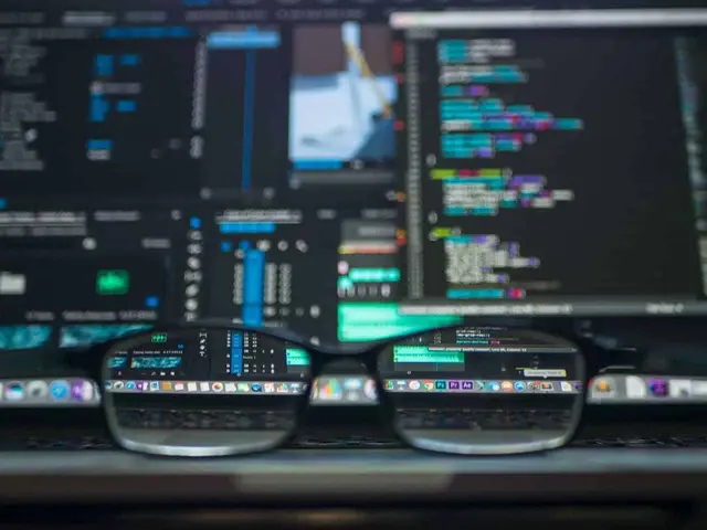Eyeglasses resting in front of several monitors with code and blurred data panels, an image of the technical work behind AI investment