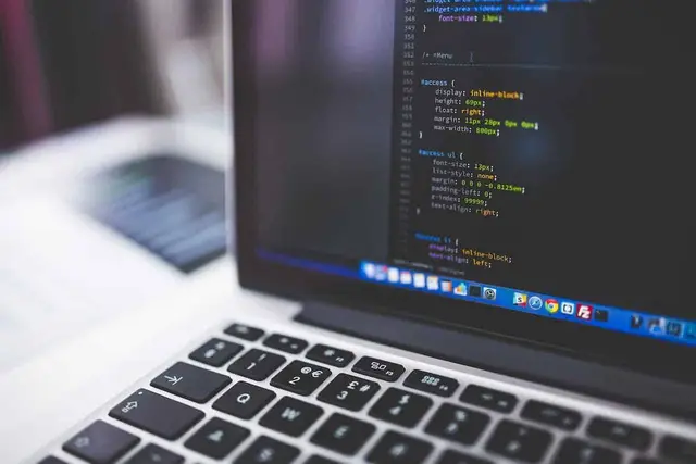 Laptop showing programming code on screen with a keyboard in the foreground and a blurred background
