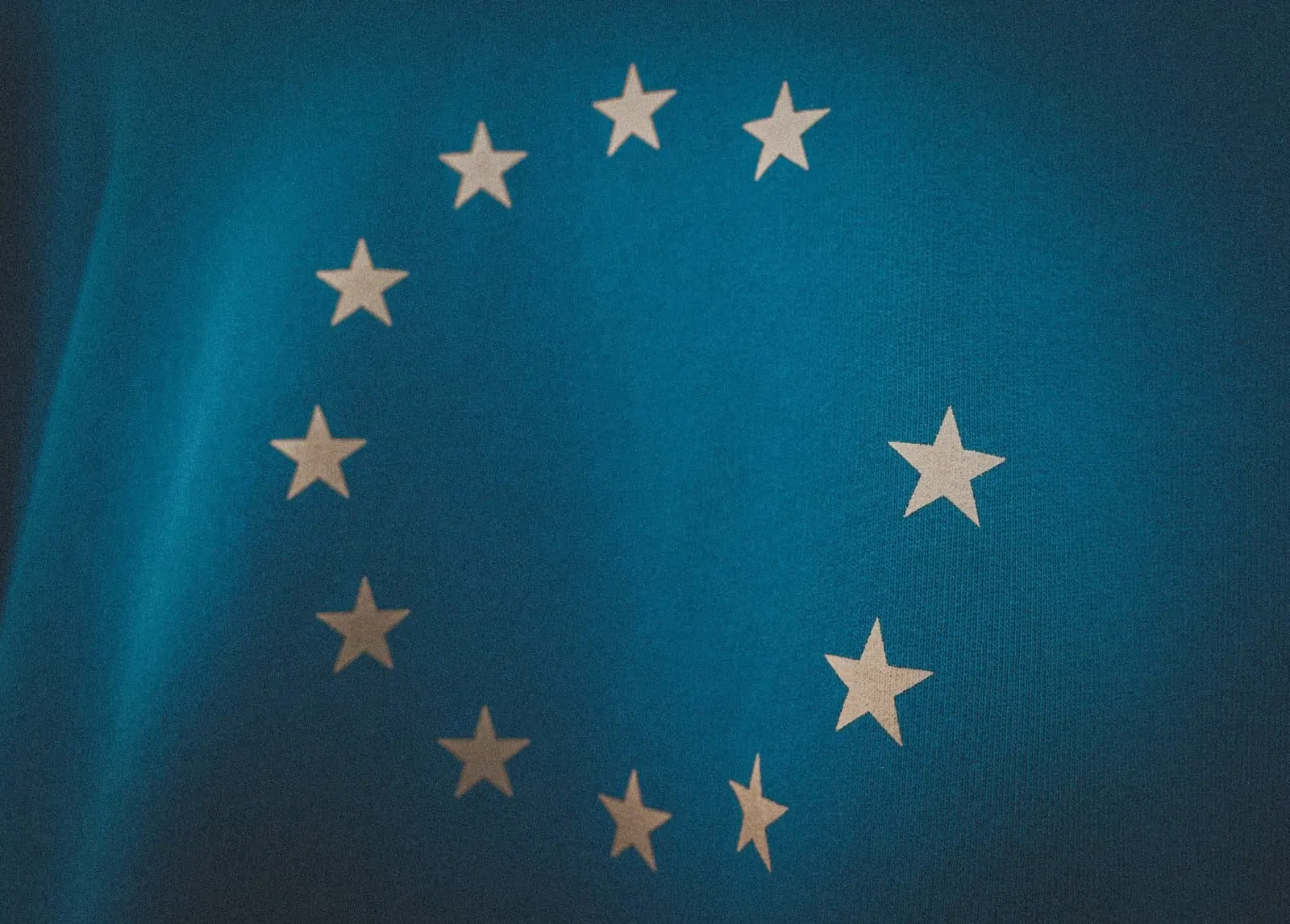 Close, dark shot of the European Union flag, with its circle of white stars on a blue background