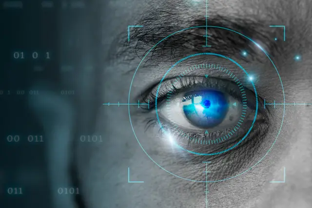 Close-up of an eye with a digital targeting overlay and binary digits in the background, in blue and gray tones.