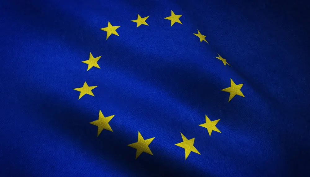 Waving flag of the European Union, with twelve yellow stars in a circle on a blue field.