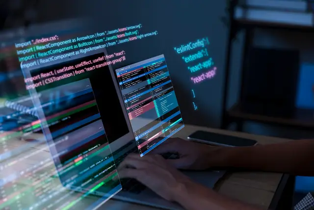Hands typing on a laptop while lines of colorful code overlap the screen, an image of software development work