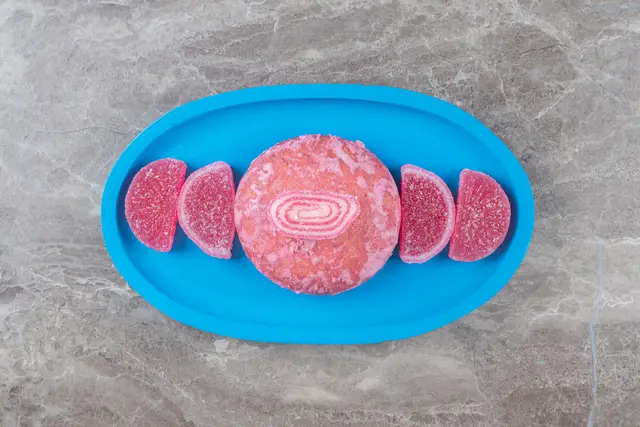 Pink pieces of cultivated meat on a blue tray on a gray marble surface