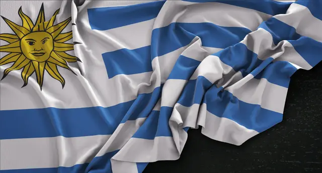 Close view of a rippled Uruguayan flag with the Sun of May on a dark surface