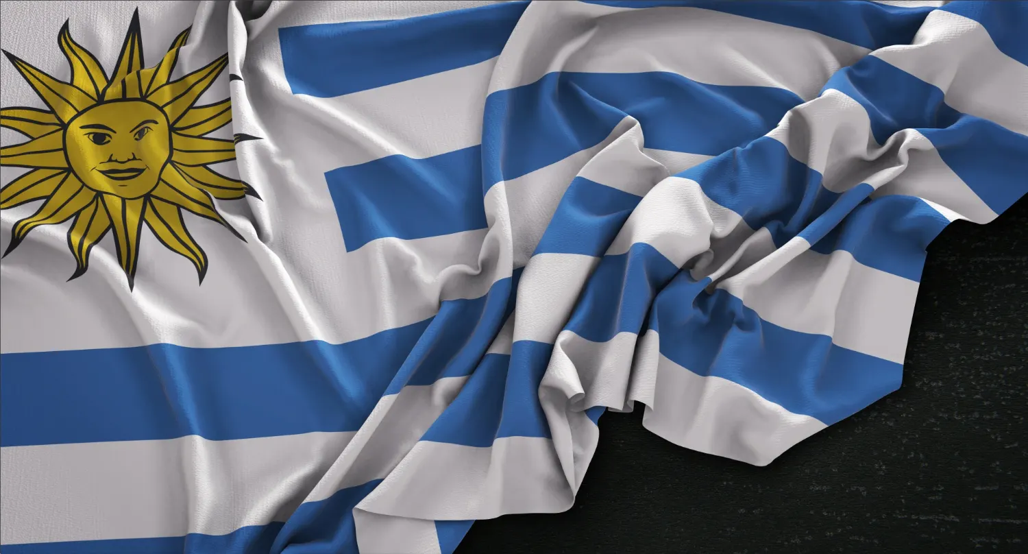 Close view of a rippled Uruguayan flag with the Sun of May on a dark surface